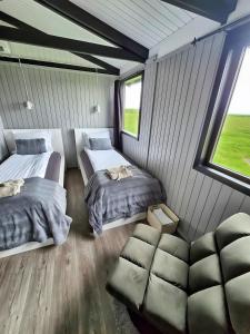 a room with two beds and a couch and a window at Aurora Cabin and Private Jacuzzi in Hvolsvöllur