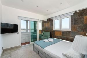 a bedroom with a bed and a chair and a television at Blife Charlya private rooms at Faro beach in FAO