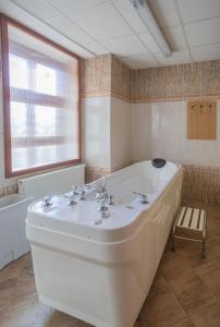 a large white tub in a bathroom with a window at Hotel Flora in Mariánské Lázně +34 photos