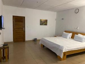 a bedroom with a bed and a television in it at Lege Bonoua in Bonoua