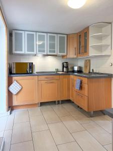 a kitchen with wooden cabinets and a tile floor at Ferienwohnungen Elbjuwel in Rathen