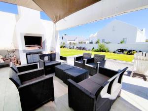 a patio with chairs and tables and a fireplace at Clarke House in Stompneusbaai