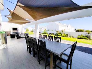 a wooden table and chairs under an umbrella on a patio at Clarke House in Stompneusbaai
