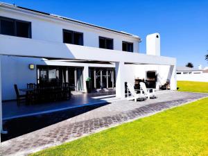 a white house with a patio and lawn at Clarke House in Stompneusbaai