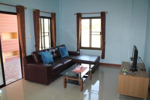 - un salon avec un canapé en cuir et une table dans l'établissement Naluemon Village FH 3-4, à Ban Phe