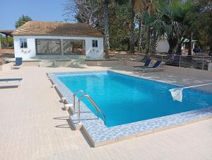 a swimming pool with blue water in front of a house at Nyantanto Eco Lodge in Gunjur +16 photos