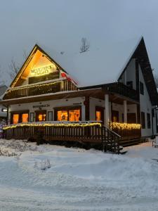 a building with christmas lights on it in the snow at Bieszczadzki Dworek Polanczyk in Polańczyk