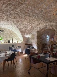 a restaurant with tables and chairs and a stone wall at Logis Hotel Restaurant L'Esquielle in Saint-Géniès-de-Malgoirès