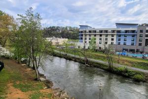 a river in front of a building next to a building at Delightful Condo Sleeps 6 Shared Pool Picnic Area in Pigeon Forge