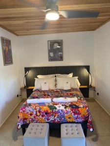 a bedroom with a bed with pillows and two stools at ALHAMBRA location saisonnière in Sainte-Rose