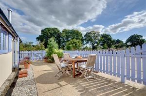 a wooden table and chairs on a patio with a white fence at 1 Bed in Biddenden oc-cb635 in Biddenden +7 photos