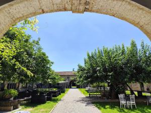 an archway over a pathway with tables and trees at Agriturismo il Vagabondo in Buttrio