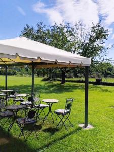 a group of tables and chairs under a white umbrella at Agriturismo il Vagabondo in Buttrio +30 photos