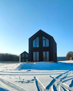 a black building in the snow with at Domki Lubikowo in Przytoczna 