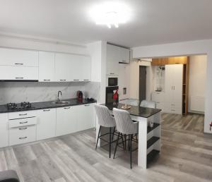 a kitchen with white cabinets and a table and chairs at Apartament in Craiova