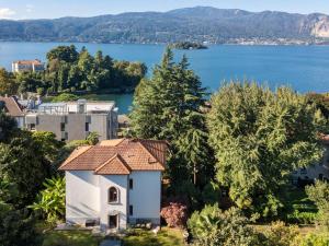 a small white building with a red roof next to the water at Villa Cedro in Verbania