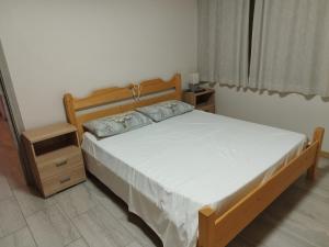 a bedroom with a bed with a wooden frame and a night stand at Da Alsido in Camporosso in Valcanale +6 photos
