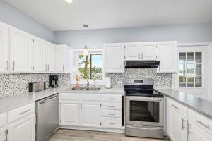 a kitchen with white cabinets and stainless steel appliances at Lakeside Getaway with Dock, Firepit, Grill in Newaygo +28 photos