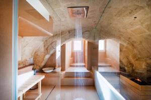 a large room with a stone wall and a bath tub at Suite San Pietro - Sassi di Matera in Matera +25 photos