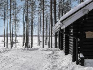a building covered in snow with trees in the background at Holiday Home Tavintupa by Interhome in Pertunmaa