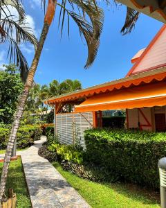 a house with a palm tree next to a sidewalk at Résidence SIMONA in Deshaies