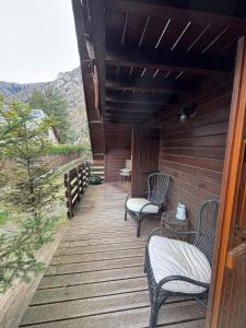 a wooden porch with two chairs and a table at Les Vaillants Chalet - Vielle Aure in Vielle-Aure