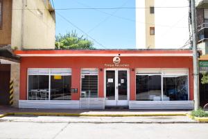 a red building with windows and doors on a street at Hotel Parque in Necochea