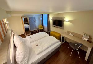 a hotel room with a white bed and a desk at Hotel Am Kornmarkt in Heidelberg +46 photos