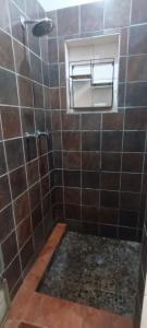 a bathroom with a shower with a tiled floor and a window at Jakkalsroep Cottage in Touwsrivier +6 photos