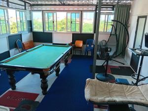 a pool table in a room with windows at BEN & LEK GUESTHOUSE in Pattaya South