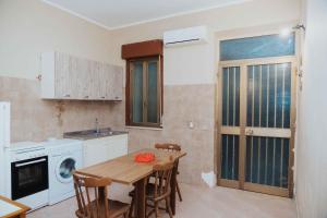 a kitchen with a wooden table with chairs and a sink at Tonnara Vista Mare in Palmi