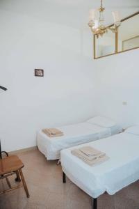 two beds in a room with a chair and a mirror at Tonnara Vista Mare in Palmi