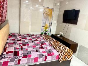 a bedroom with a bed with a colorful comforter at Santhosh hotel in Khammam +1 photo