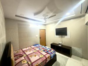 a bedroom with a bed and a tv on the wall at Santhosh hotel in Khammam
