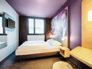 a bedroom with a bed with a purple wall at B&B Hotel Augsburg-West in Augsburg +17 photos