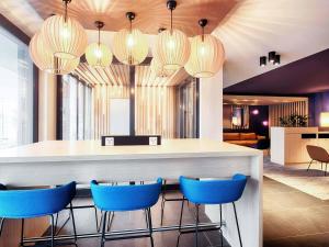 a lobby with a bar with blue chairs and lights at B&B Hotel Augsburg-West in Augsburg