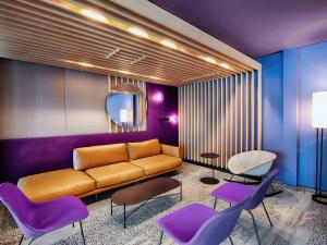 a living room with a couch and purple chairs at B&B Hotel Augsburg-West in Augsburg
