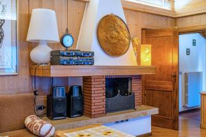 a living room with a brick fireplace and a lamp at Tizzi Home in Alleghe