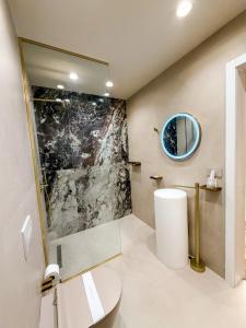 a bathroom with a shower and a sink and a mirror at Vatër Selected Rooms in Tirana