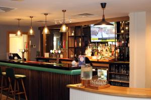a bar in a restaurant with a tv behind it at Holiday Inn Basingstoke by IHG in Basingstoke