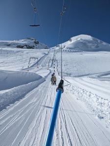 two people on a ski lift in the snow at Alpina Peaks in Saas-Fee