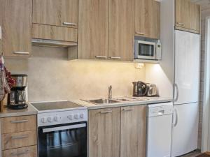 a kitchen with a sink and a white refrigerator at Holiday Home Pikkuhukka by Interhome in Hyrynsalmi