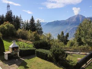 a garden with a small oven in the grass with a mountain at Chalet Chalet Chante Neige by Interhome in Riddes