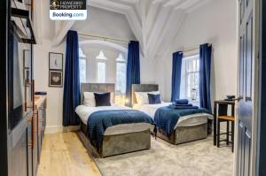 two beds in a bedroom with blue curtains at Large 6BDR House By Homebird Property Management Short Lets & Serviced Accommodation Leeds With Secured Parking & Garden Area in Leeds