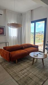 a living room with a brown couch and a table at 1BR Serviced Apt with Pool & Premium Amenities in Oroklini +1 photo