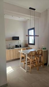 a kitchen with a white table and some chairs at 1BR Serviced Apt with Pool & Premium Amenities in Oroklini