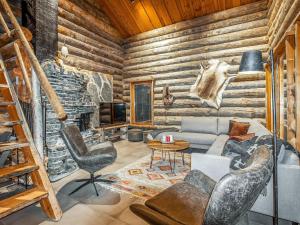 a living room with a couch and chairs in a log cabin at Holiday Home Kelohippu 2 by Interhome in Pyhätunturi