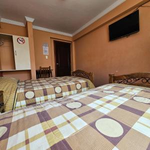 a hotel room with two beds and a flat screen tv at Bolivian Heights Hostel in La Paz +34 photos
