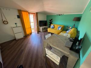a living room with a yellow couch and a television at Attico Vicky in Porto Azzurro