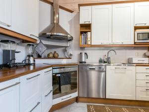 a kitchen with white cabinets and stainless steel appliances at Holiday Home Otsonherra by Interhome in Pyhätunturi